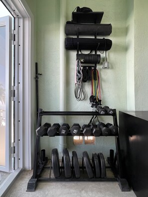 A home gym with a weight bench, dumbbells, and resistance bands. - Waterfront Hideaway · 100-Ft Dock · Hot Tub with TV — Your Keys Escape (Key Largo)