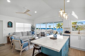 A modern kitchen with a large island, white cabinetry, and a view of the ocean. - Waterfront Hideaway · 100-Ft Dock · Hot Tub with TV — Your Keys Escape (Key Largo)