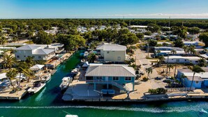 A coastal residential area with houses, a marina, and a clear sky. - Waterfront Hideaway · 100-Ft Dock · Hot Tub with TV — Your Keys Escape (Key Largo)