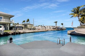 Un port esportiu amb vaixells, una piscina i un edifici amb un balcó.