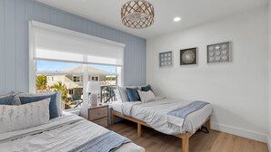 A bedroom with two beds, a window with a view, a ceiling fan, and wall art. - Waterfront Hideaway · 100-Ft Dock · Hot Tub with TV — Your Keys Escape (Key Largo)