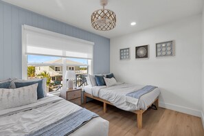 Ein Schlafzimmer mit zwei Betten, einem Fenster mit Blick und einem Deckenventilator, sowie Wandbildern.