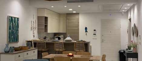 Un salon moderne avec un coin repas, une cuisine à l’arrière-plan et un luminaire au plafond.