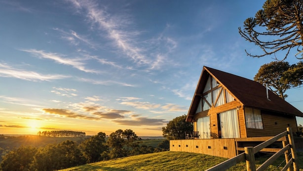 A wooden cabin with a sloped roof, large windows, and a wooden deck.