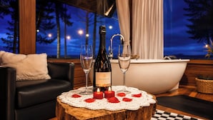 A cozy room with a bottle of wine, two glasses, and candles on a wooden table.