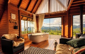 Interior de una cabaña de madera con una bañera grande, un sofá y un perro.