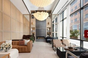 A modern living room with a fireplace, large windows, and a chandelier. - 10 Min Soho NYC Comfort Suite (Jersey City)