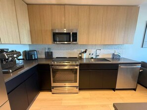 Uma cozinha moderna com eletrodomésticos de aço inoxidável, armários de madeira e painel de azulejos.
