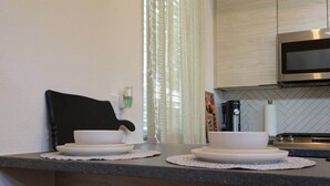 A kitchen with a microwave, a coffee maker, and a sink. - Mid-Century Tiny House (Austin)