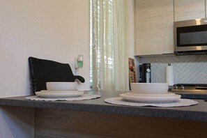 A kitchen with a microwave, a coffee maker, and a sink. - Mid-Century Tiny House (Austin)