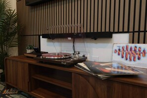 A wooden reception desk with a turntable, a small plant, and a wall-mounted television. - Mid-Century Tiny House (Austin)