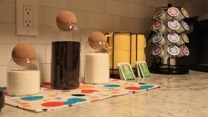 A kitchen counter with a coffee machine, a candle, and a set of coasters. - Retro Oasis (Austin)