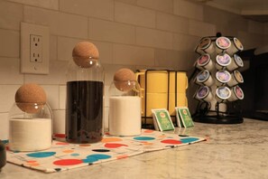 Eine Küchenarbeitsplatte mit einer Kaffeemaschine, einer Kerze und einer Untersetzersammlung.