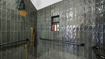 Un baño con ducha, barra de apoyo y estante con artículos de aseo.