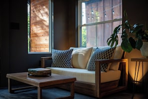 Un coin salon confortable avec un canapé et des fauteuils, une petite table et une plante en pot.