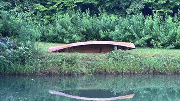 A calm body of water with a wooden bridge and dense greenery in the background.