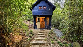 A wooden cabin with a porch, a door, and a window.