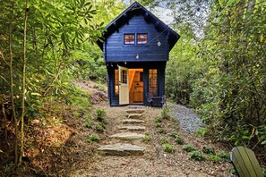 A wooden cabin with a porch, a door, and a window.
