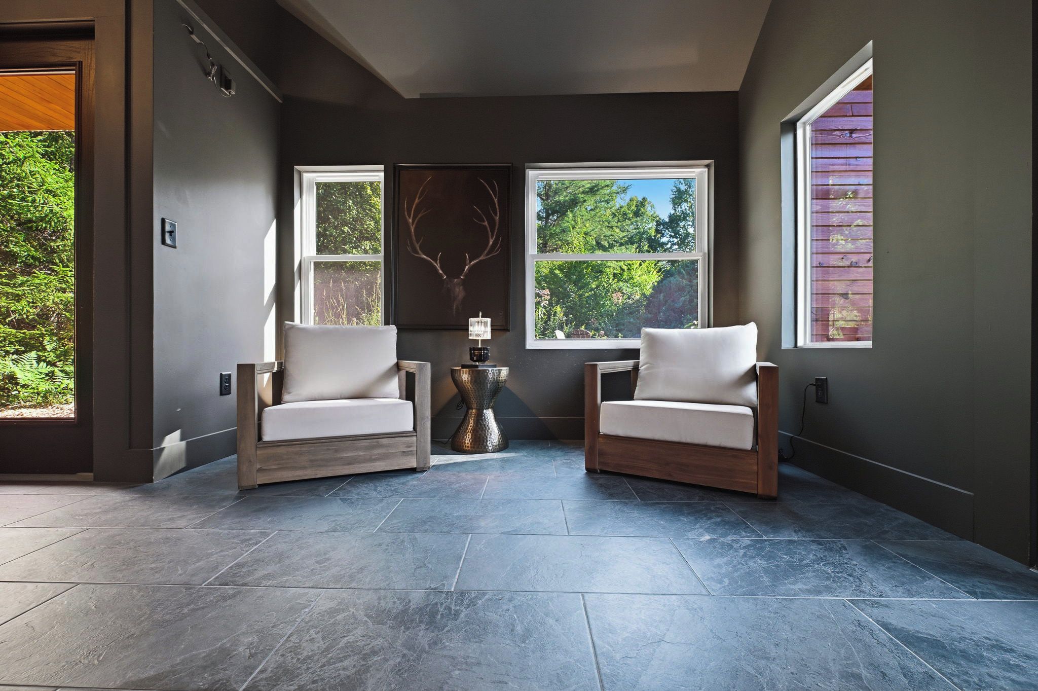A room with two armchairs, a fireplace, and large windows.