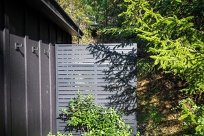 A grey metal fence with horizontal slats, a metal gate, and a small plant in front.
