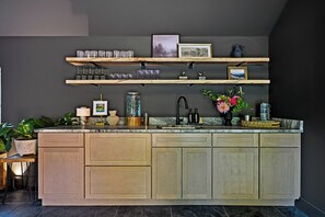 Una cocina con una isla central, armarios de madera y una pared oscura.