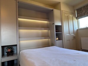 A bedroom with a bed, built-in wardrobe, and a radiator.