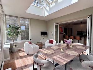 Un comedor moderno con techo alto, tragaluces y vistas al exterior.
