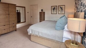 Une chambre à coucher avec un lit, une commode, un miroir et deux tableaux encadrés accrochés au mur.