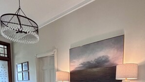 Un couloir avec une console en bois, deux lampes, un tableau et un radiateur.