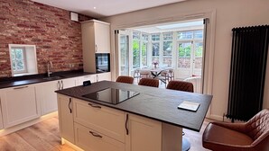 Une cuisine moderne dotée d’un îlot central, de meubles blancs et d’un mur d’accent en briques.