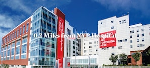A modern building with a prominent red banner and a glass facade. - Modern 1-Bedroom Apartment with AC in Flushing (FLUSHING)