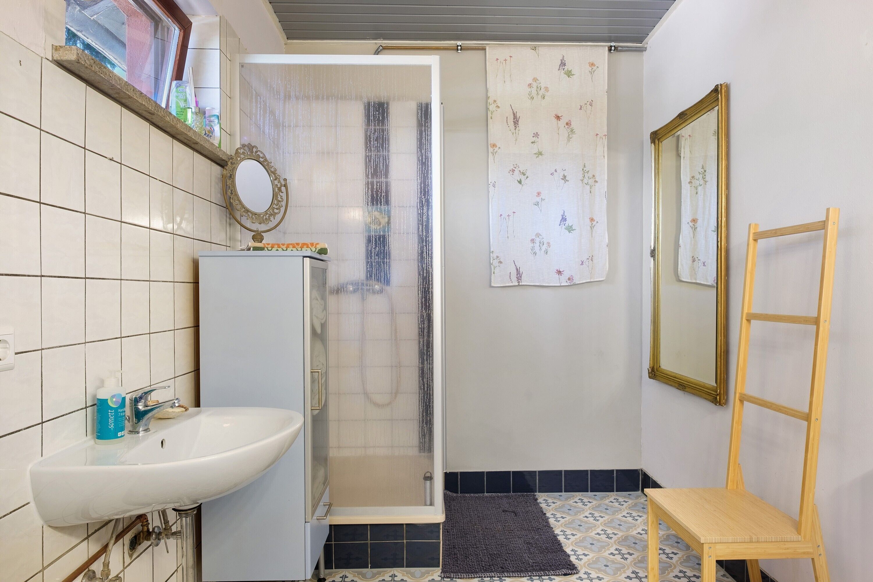 Ein Badezimmer mit Waschbecken, Dusche und Spiegel.