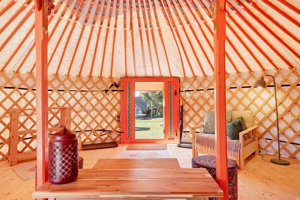 A yurt interior with a wooden table, a decorative vase, and a sofa.