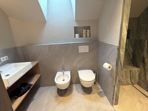 Ein modernes Badezimmer mit integriertem Bidet, Toilette, Waschtisch und Duschbereich.