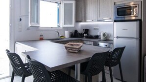 Une cuisine moderne dotée d’un îlot central, de tabourets de bar, d’un four à micro-ondes et d’un réfrigérateur.