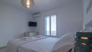 Une chambre à coucher avec un lit, une télévision, une fenêtre et un luminaire au plafond.