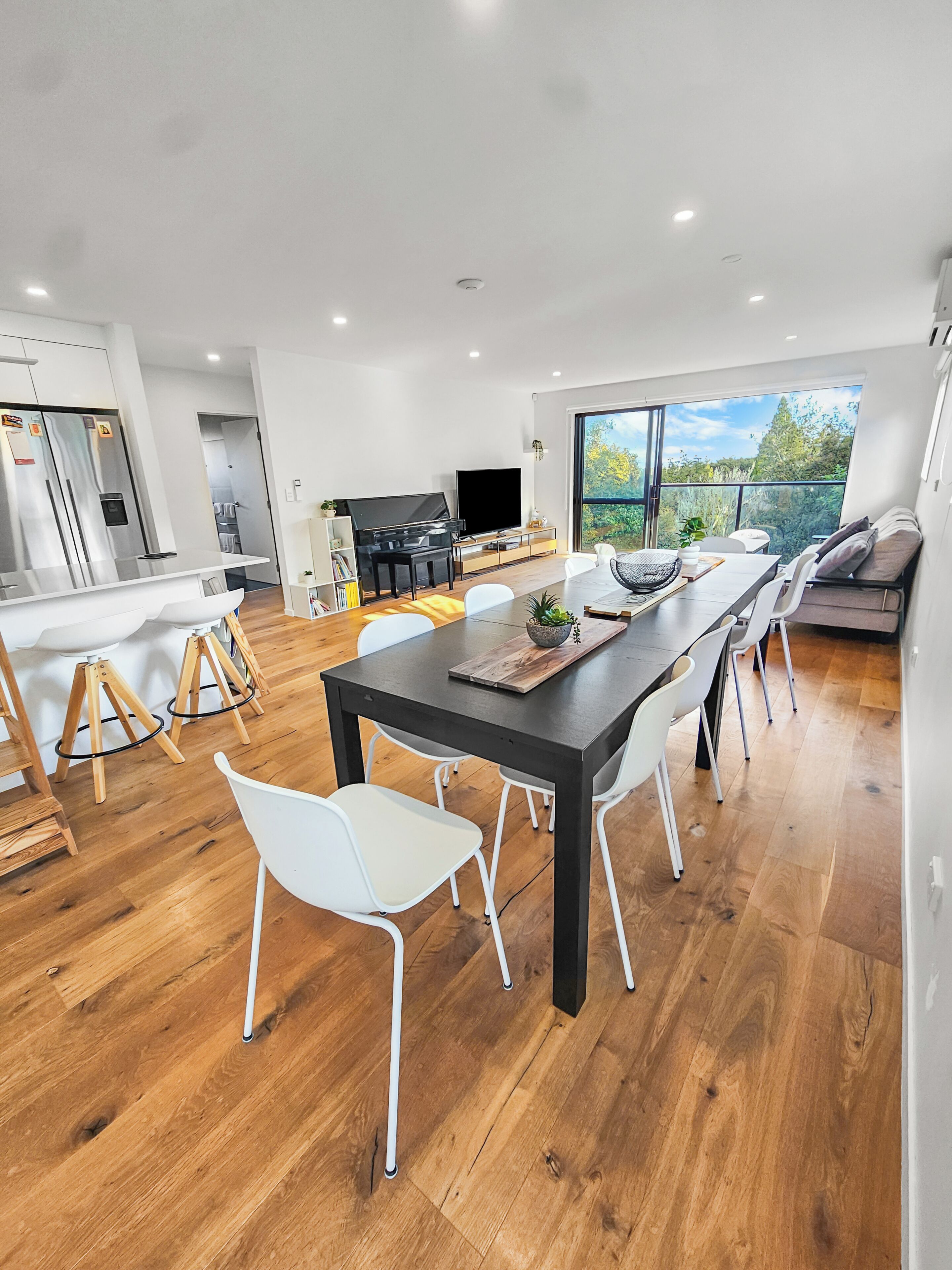 Una cocina moderna con comedor, televisor y piano.
