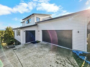 Ein zweistöckiges Haus mit Garage, einer kleinen oberen Terrasse und einem Betonauffahrtsweg.