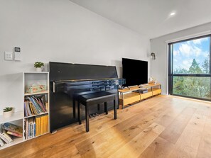 Una sala de estar moderna con un piano, un televisor de pantalla plana y una estantería.