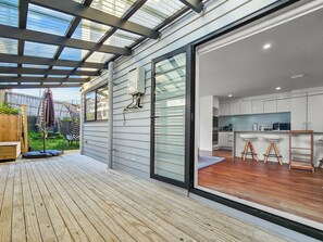 Eine moderne Küche mit weißen Schränken und Holzboden, verbunden mit einer Terrasse mit Glasdach.