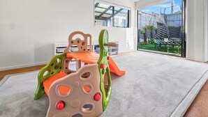 A room with a play area featuring a climbing structure and a large sliding glass door leading to an outdoor space. - Birkenhead Bliss | Serene 4Bed Home | Quiet, Views (Birkenhead)