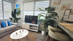 Ein Wohnzimmer mit Sofa, Fernseher, Couchtisch und Barbereich.