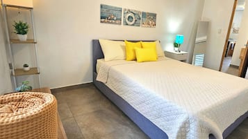 Ein Schlafzimmer mit einem Bett, Kissen, einem Nachttisch mit Lampe, einer Wandablage mit Pflanzen und einer Tür zu einem weiteren Raum.