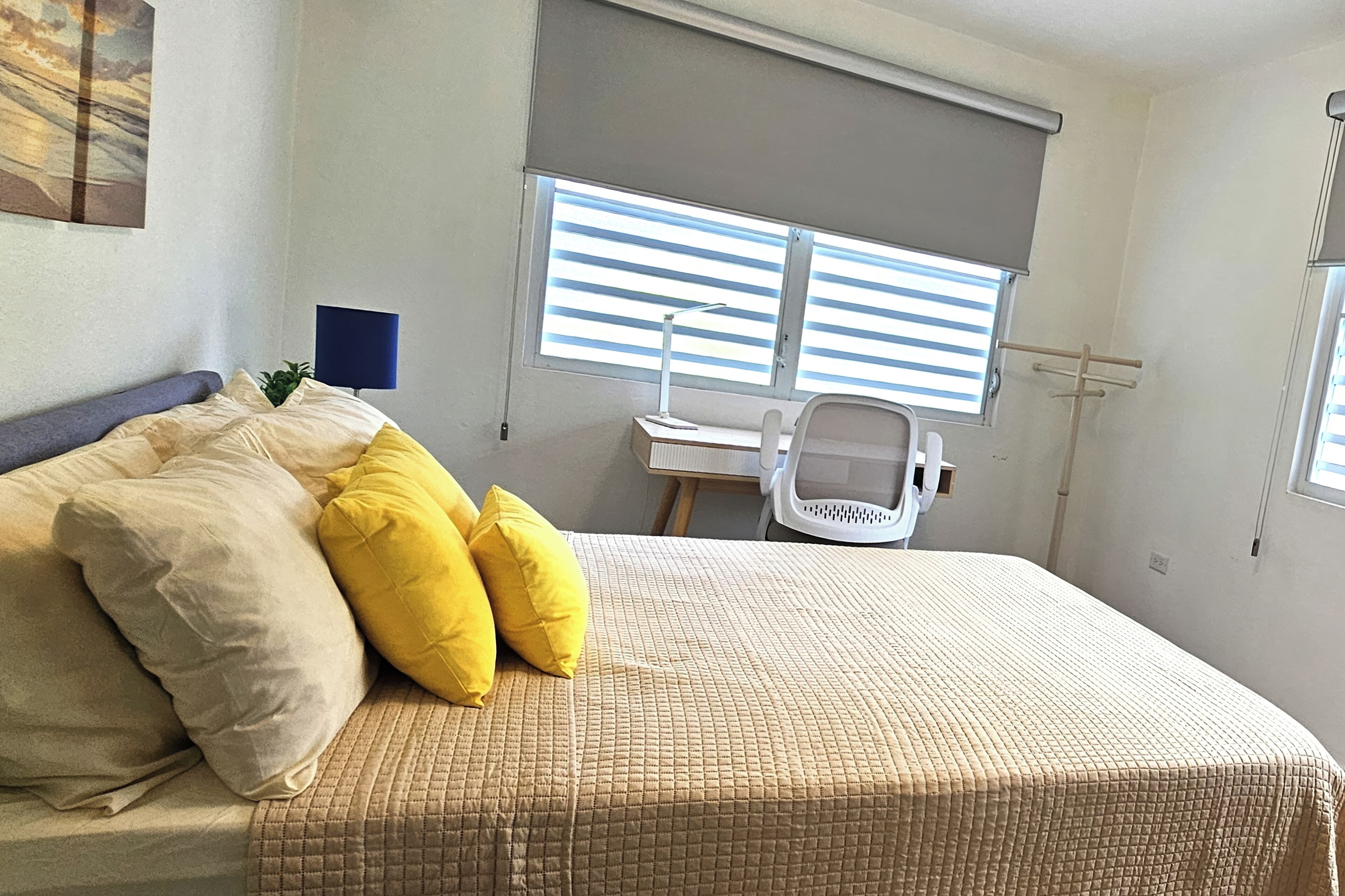 Un dormitorio con una cama, un escritorio y una silla.