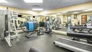 Une salle de sport équipée de divers appareils, notamment des tapis de course, des appareils de musculation et un mur avec des miroirs.