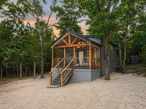 Eine Hütte mit Veranda, Holztreppe und Kiesgrundstück.