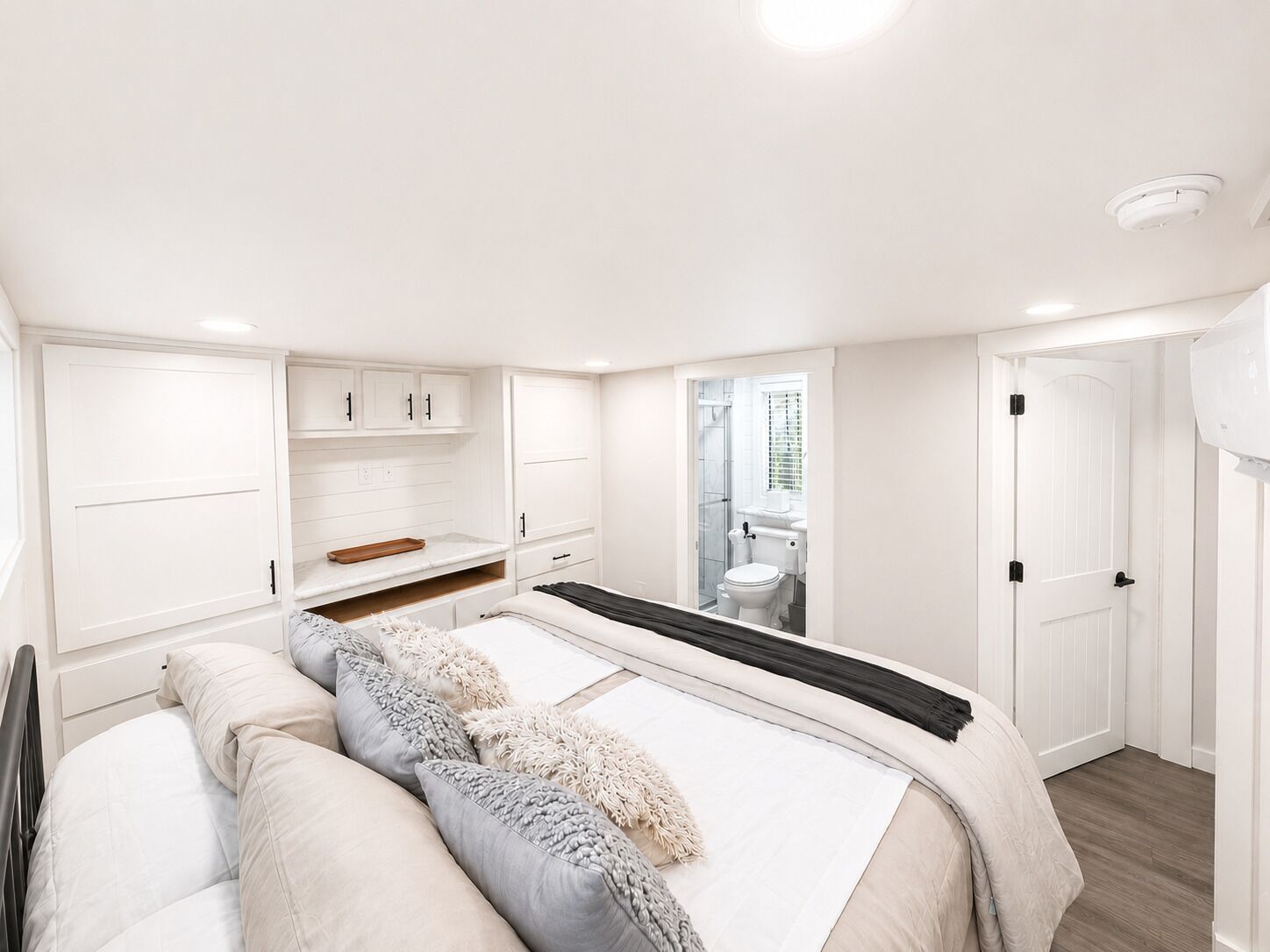 A bedroom with a bed, bedside tables, a wardrobe, and a bathroom visible through an open door.