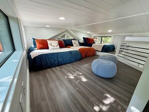 Ein Schlafzimmer mit einem großen Bett, einem Fenster, einer Decke mit Einbuchtungslampen und einem Holzboden.