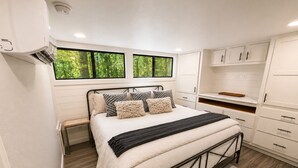 Quarto com cama, janela, guarda-roupa e secretária embutida.