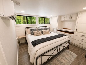 Ein Schlafzimmer mit Bett, Fenster, Kleiderschrank und integriertem Schreibtisch.